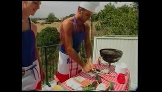 Watch the video about Young Gregg Clarke helps blond s.-hunter Paul Morgan to cook sausages and fish frames on barbeque grill